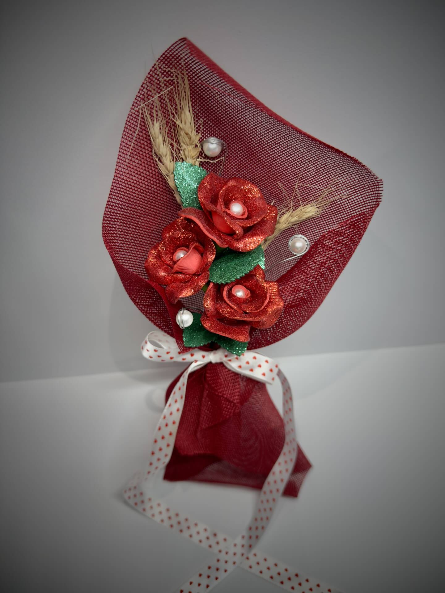 Arranjo artesanal de rosas vermelhas brilhantes com laço branco