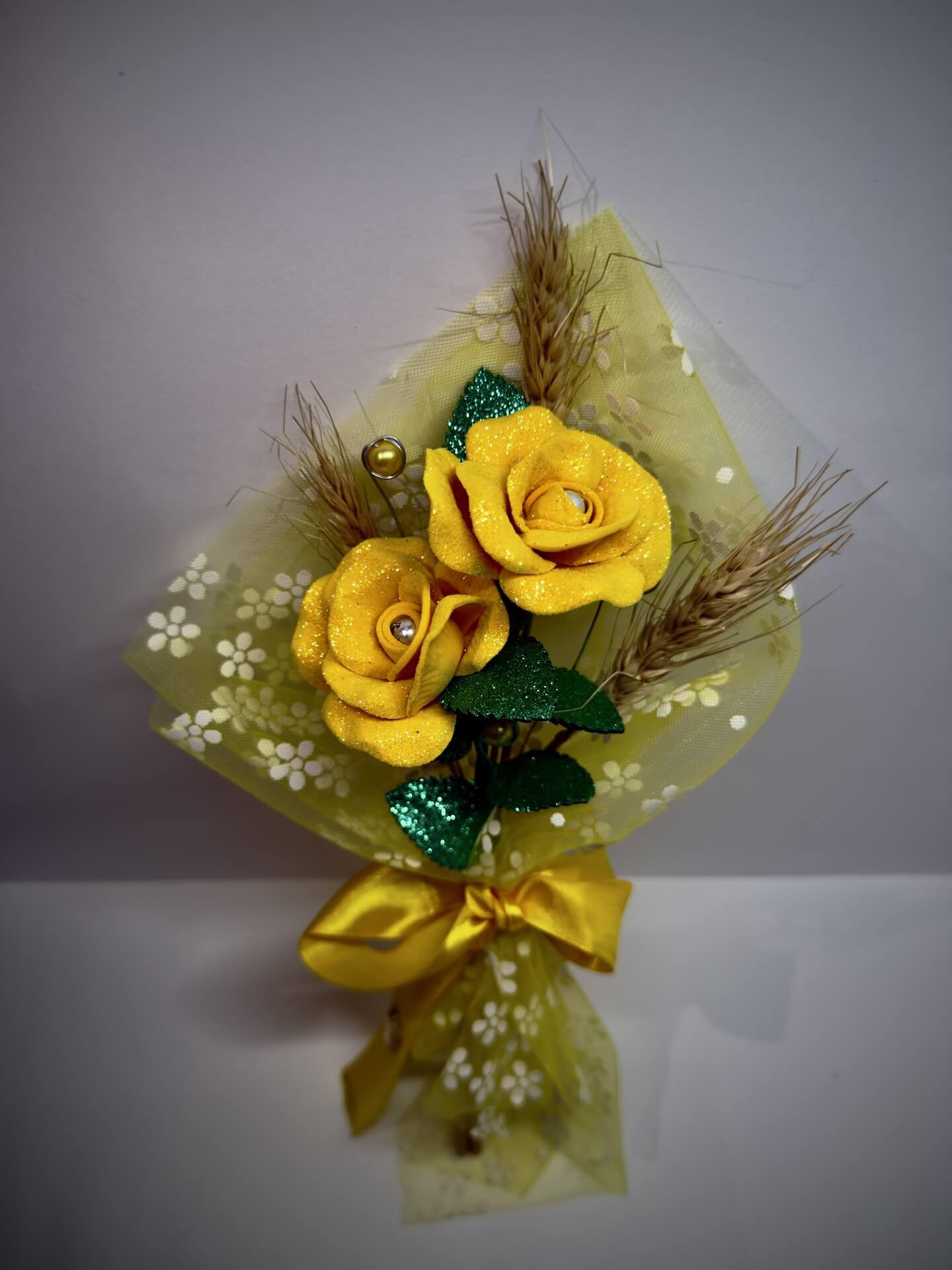 Arranjo artesanal com duas rosas amarelas e laço amarelo